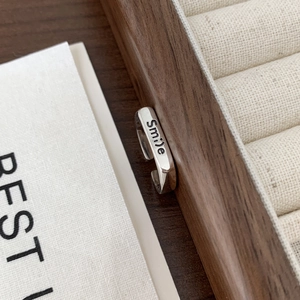 Detail shot of 925 sterling silver smile ring resting on a dark wooden jewelry box