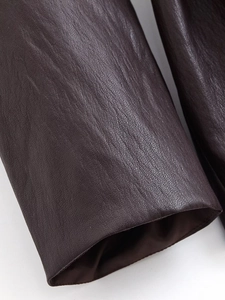 Detail of dark brown faux leather coat sleeve with premium texture and clean tailoring