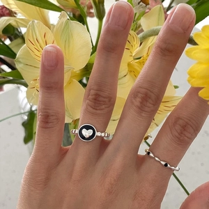 Detail of S925 silver heart ring with black enamel inlay and twisted band texture
