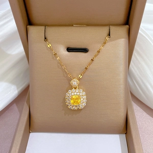 Détail du collier en titane doré avec pierre carrée jaune et contour en pierres blanches