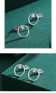 Macro shot of silver round stud earrings with clear sparkling zircon on green surface