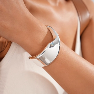 Close-up of polished silver twisted cuff bracelet with irregular geometric design on wrist