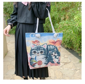 Detail of embroidered cat and goldfish pattern on a canvas tote with rope handles