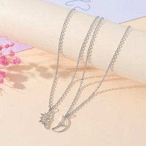 Minimalist stainless steel sun and moon pendant necklaces for couples on warm background