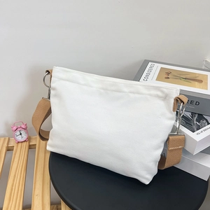 Detail of white canvas tote bag with thick texture and dark brown braided strap