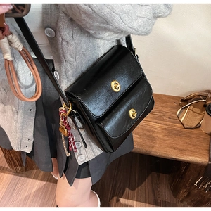 Detailed view of the black retro crossbody bag with dual gold twist-lock closures