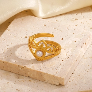 Elegant gold crown ring with white pearl inlay on stone and silk background