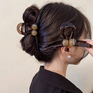 Large tortoiseshell acrylic hair claw clip with amber beads on an elegant hair updo