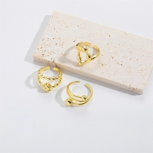 Three-piece set of vintage gold knot-design adjustable open rings on a beige stone slab