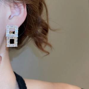 Close-up of geometric square drop earrings with cubic zirconia on model ear