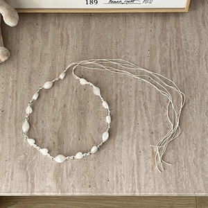 Detail of bohemian braided belt with white textured beads and silver metal spacers