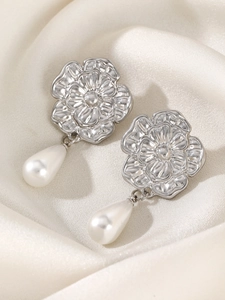 Detailed close-up of silver floral earrings with elegant white teardrop pearls on silk