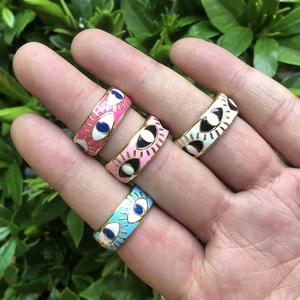 Detail view of colorful evil eye enamel rings in pink, white and blue on hand