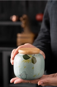 Detailed view of hand-held ice-cracked glaze ceramic tea canister with rabbit pattern