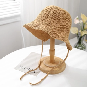 Détail de la texture du chapeau cloche en paille avec bride sur support bois
