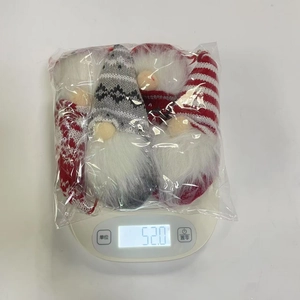 Weight measurement of 4-piece Christmas gnome plush ornaments in packaging on digital scale