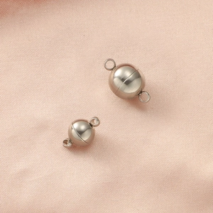 Close-up of spherical silver magnetic clasps for jewelry making on beige fabric