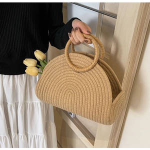 Detail of a natural tan woven semicircular handbag with circular handles and tulips