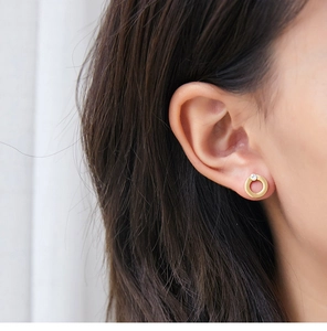 Macro view of geometric gold ring earring with diamond accent on model ear