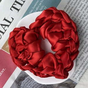 Elegant red satin woven heart scrunchie on vintage newspaper background