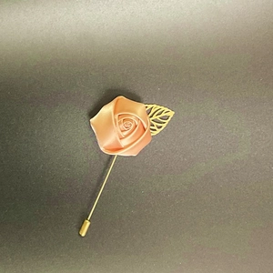 Detail of champagne gold satin rose brooch with a delicate hollow metal leaf on long pin