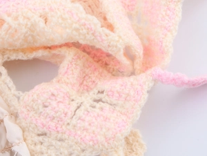 Close-up of beige and pink crochet knit fabric showing detailed floral hollow pattern