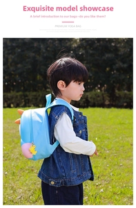 Close-up of light blue cartoon dinosaur backpack with orange spikes and a cute charm