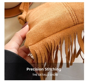 Detailed view of reinforced double stitching and long suede tassels on brown crossbody bag