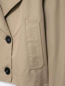 Close-up of khaki trench coat fabric featuring black buttons and detailed twill texture