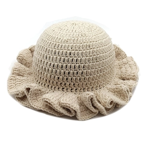 Detail of beige crochet knit bucket hat showing ruffled brim and thick stitch texture