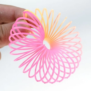 Hand stretching a pink and yellow gradient plastic spring toy against a white background
