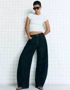 Full view of high waist wide leg jeans in dark blue on a model with white crop top
