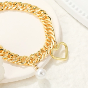 Detail of gold Cuban link chain with hollow heart pendant and white baroque pearl charm