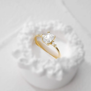 Macro detail of luxury square-cut gemstone ring on a minimalist white textured base