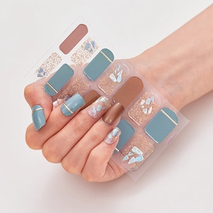Detail view of laser bronzing nail stickers with blue shells and gold glitter patterns