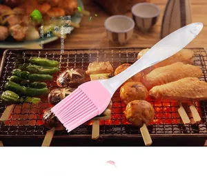 Pink silicone BBQ brush with transparent handle on grill, heat resistant and detachable