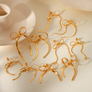 Close-up of golden bow-shaped earrings with delicate snake chain texture details