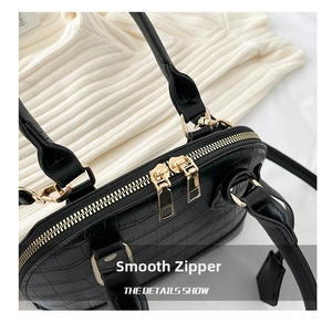 Detail of black faux leather shell bag showing crocodile texture and gold zippers