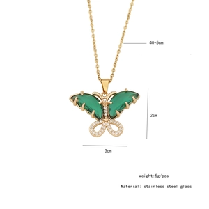 Detailed view of golden butterfly pendant with green glass wings and dimensions on white back