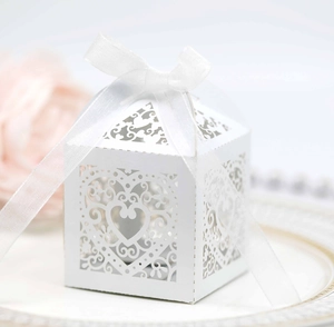 Close-up of laser-cut heart candy box with elegant white ribbon for wedding favors