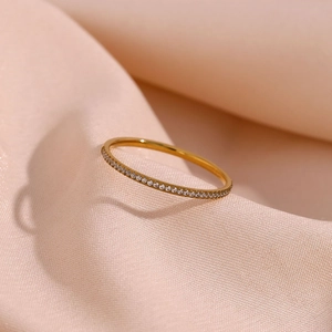 Detailed shot of gold plated stainless steel ring with micro zircons on pink silk cloth