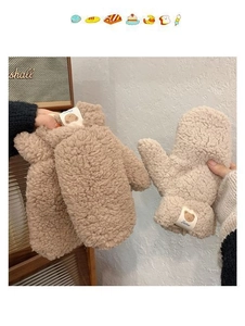 Close-up of plush lamb wool mittens featuring cute cartoon bear patches and thick texture