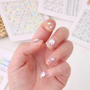 Macro shot of colorful AB rhinestone nail art with heart and floral crystal patterns