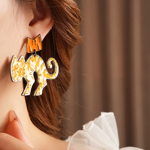 Detail of cute cat earrings in orange and white enamel worn by a female model