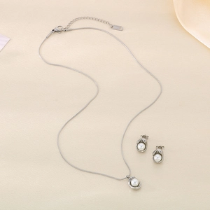 Close-up of polished silver necklace and stud earrings set with elegant white pearls