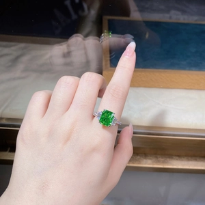 Close-up of radiant cut emerald green zircon ring on hand with trapezoid side stones