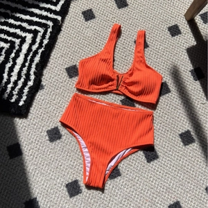 Bright orange ribbed high waist two-piece swimsuit with V-shaped metal hardware detail