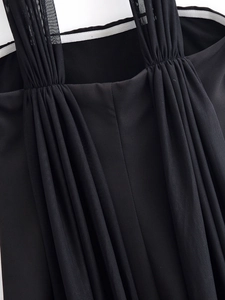 Dettaglio di cuciture in rete nera e spallina plissettata su un abito a fascia nero