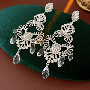 Detailed macro view of silver flower earrings with tassels and crystals on velvet