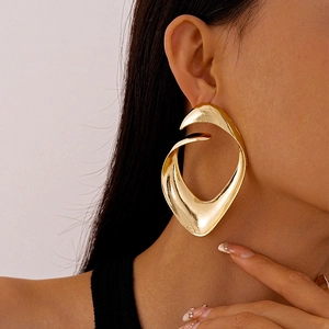 Close-up of model wearing oversized irregular golden geometric earrings with metallic finish